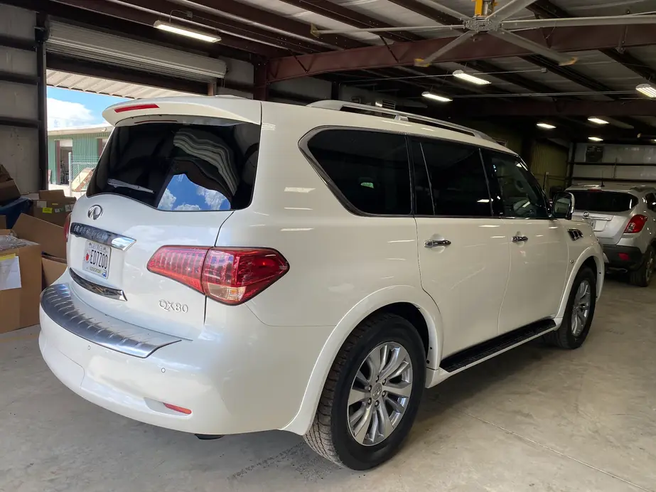 White Infiniti QX80 in the shop bay with freshly tinted rear glass, roller door open
